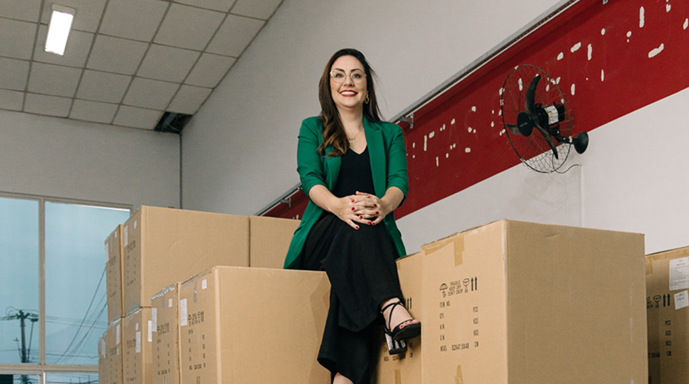 Camila no galpão entre caixas da operação